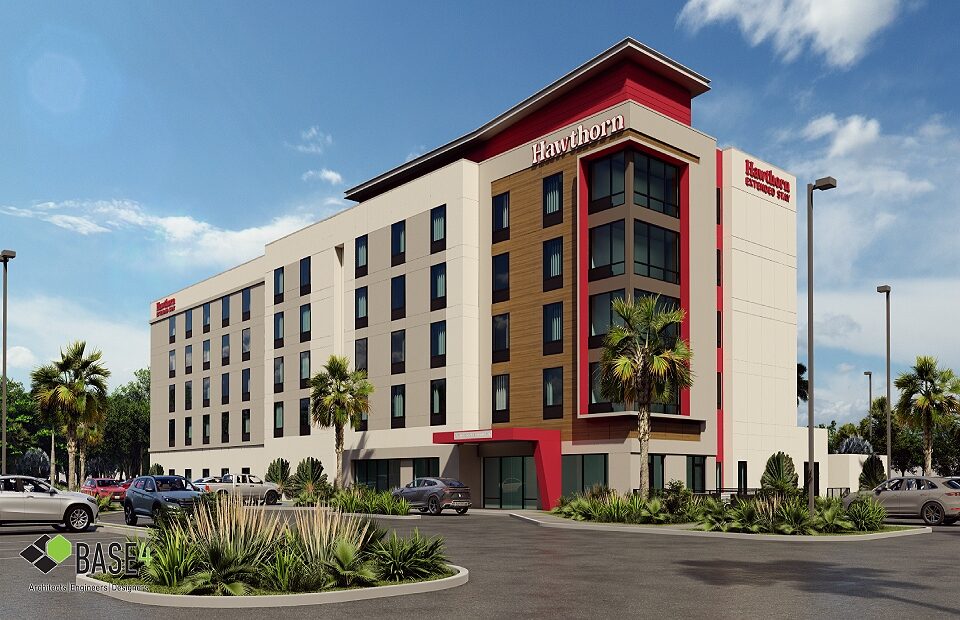 Modern Hawthorn Extended Stay Hotel exterior during sunset showcasing the hotel's multi-story architecture with vibrant red accents, landscaped surroundings, and parked cars.