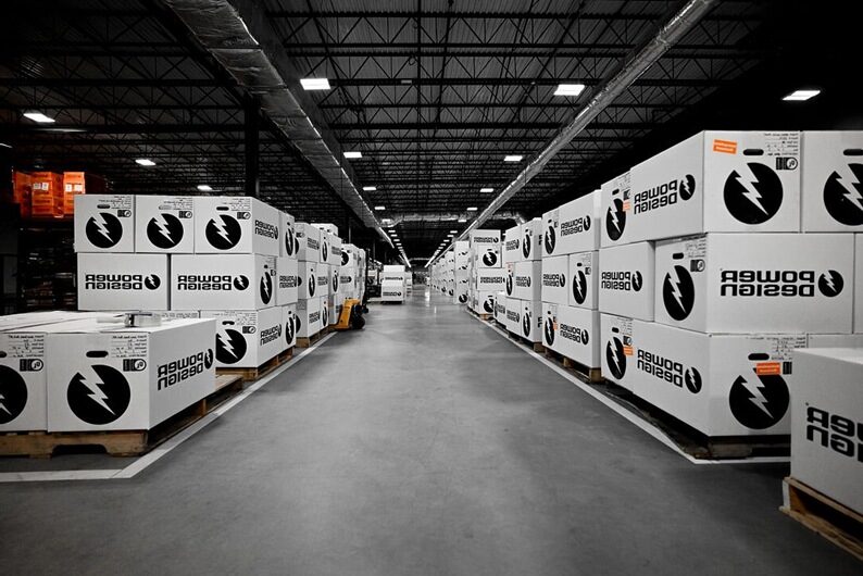 Warehouse interior showing rows of Power Design prefabricated electrical components boxes, emphasizing large-scale production and organized storage.
